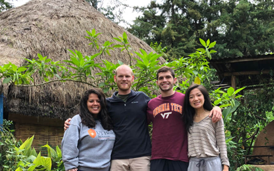 Left to right: Claudia Samaniego, DS4, Keith Usry, DS4, Luke Seiler, DS4, and Michelle Zhou, DS3, pose in front of the community's dining hut.