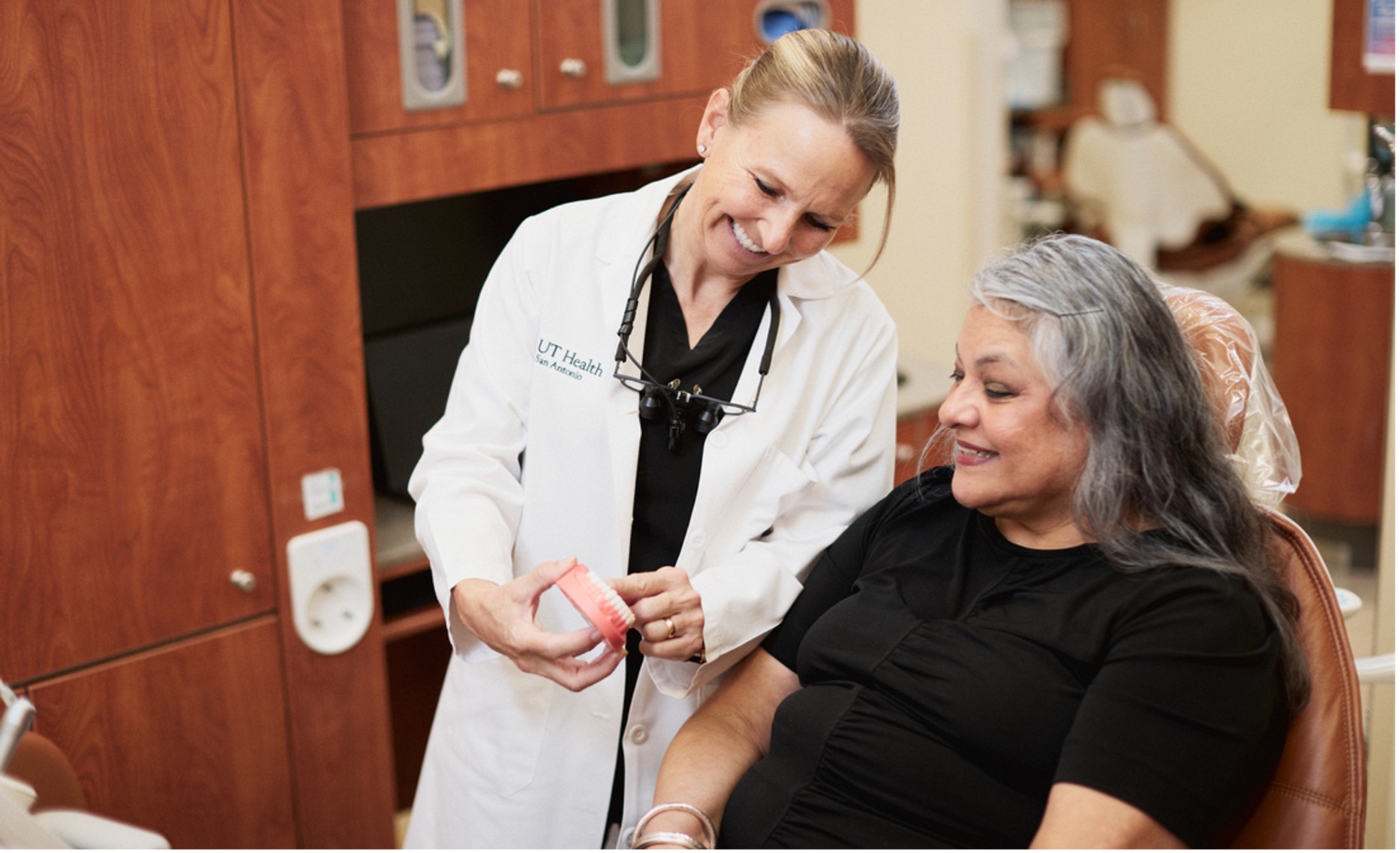 Dentist showing patient a set of dentures in her hand.jpg