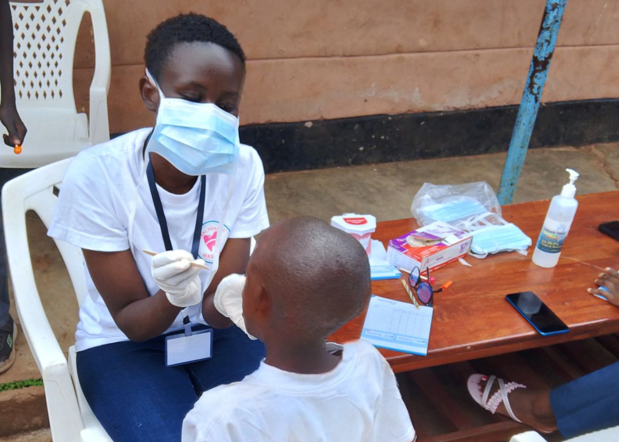 Kenyan dental assistant checking young childs mouth